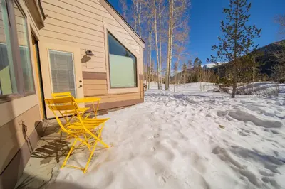 a yellow chair sitting on a porch in the snow at Quicksilver 1609 by SummitCove Lodging in Keystone