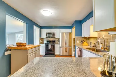 a large kitchen with white cabinets and blue walls at 2 Mi to Olde Town! Pet-Friendly Haven with Sunroom in Arvada