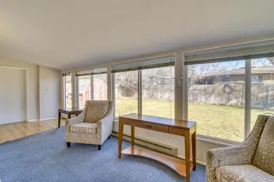 a living room with a desk and chairs and windows at 2 Mi to Olde Town! Pet-Friendly Haven with Sunroom in Arvada