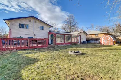 a white house with a red fence in a yard at 2 Mi to Olde Town! Pet-Friendly Haven with Sunroom in Arvada