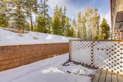 a snow covered balcony with a fence and trees at Heated Pool Access at Winter Park Base Camp! in Winter Park