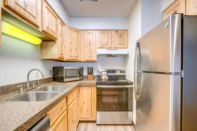 a kitchen with wooden cabinets and a stainless steel refrigerator at Walk to Main St! Ultimate Winter Park Getaway in Winter Park