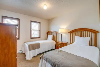 a bedroom with two beds and a dresser and two windows at Heated Pool and Hot Tub! Winter Park Mtn Retreat in Winter Park