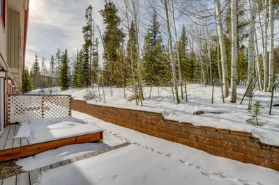 a snow covered patio with a bench on a brick wall at Heated Pool and Hot Tub! Winter Park Mtn Retreat in Winter Park