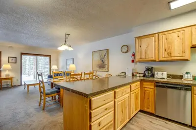 a kitchen with wooden cabinets and a dining room at Heated Pool and Hot Tubs at Dtwn Winter Park Condo! in Winter Park