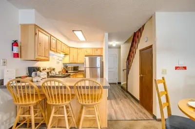 a kitchen with wooden cabinets and a table and chairs at 3 Mi to Winter Park Slopes! Unit with Pool and Hot Tub in Winter Park