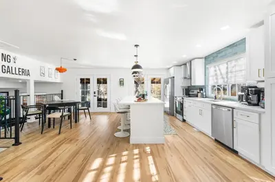 a kitchen with white cabinets and a dining room at NEW Olde Town Arvada 5BR Luxe Mini Golf Hot Tub Arcade Cinema Gym in Arvada