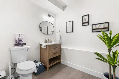 a bathroom with a toilet and a sink and a mirror at NEW Olde Town Arvada 5BR Luxe Mini Golf Hot Tub Arcade Cinema Gym in Arvada