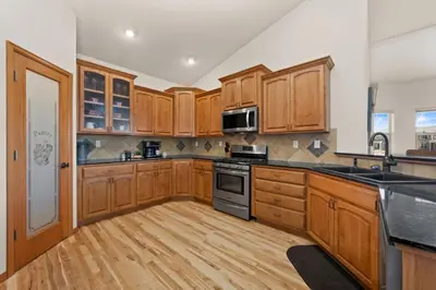a large kitchen with wooden cabinets and wooden floors at Cabin-Style Group Retreat Near RMNP, Lakes and Golf in Loveland