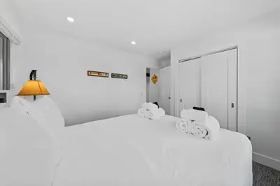 a white bedroom with two white beds and a lamp at Granby Mountain - Forest Views, Hot Tub & Fire Pit in Granby