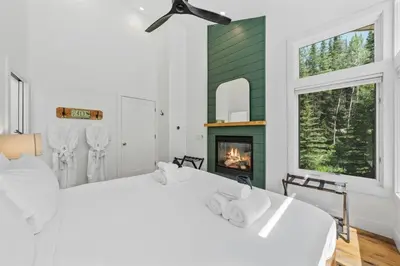 a bedroom with a white bed and a fireplace at Granby Mountain - Forest Views, Hot Tub & Fire Pit in Granby