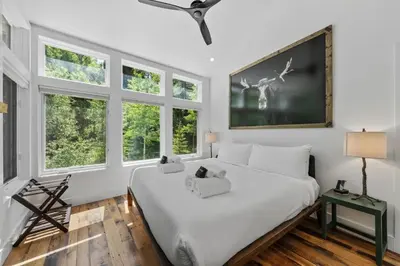 a bedroom with a large white bed with windows at Granby Mountain - Forest Views, Hot Tub & Fire Pit in Granby