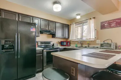 a kitchen with black cabinets and a large refrigerator at 4 Mi to Dtwn Loveland Home with Hot Tub and Yard in Loveland