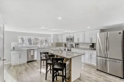 a kitchen with white cabinets and a kitchen island with stools at Black Hawk Getaway with Hot Tub cabin in Black Hawk