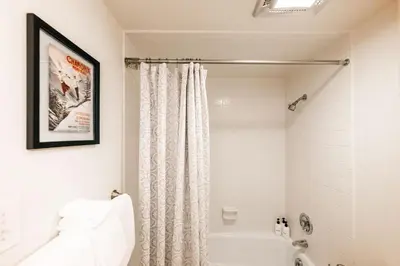 a white bathroom with a shower curtain and a tub at Spacious Family Condo - Walk to Dillon Reservoir in Dillon