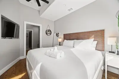 a white bedroom with a large white bed and a tv at Heart of Downtown City Views Deck BBQ in Denver