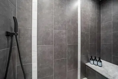 a bathroom with a shower with gray tiles at Heart of Downtown City Views Deck BBQ in Denver
