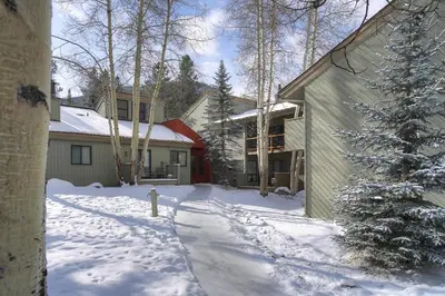 a snow covered yard with a house and a christmas tree at Flying Dutchman 1201 by SummitCove Lodging in Keystone
