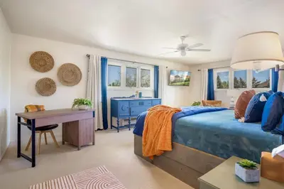 a bedroom with a blue bed and a desk and windows at Mid-Century Mod - 7 BR Sleeps 22 - Hot Tub & Game Room in Westminster