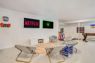 a living room with chairs and a television on a wall at Mid-Century Mod - 7 BR Sleeps 22 - Hot Tub & Game Room in Westminster