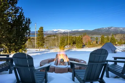 a fire pit in the snow with two chairs at Peaks Perch home in Granby