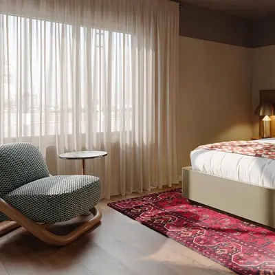 a bedroom with a bed and a chair next to a window at All Inn in Denver