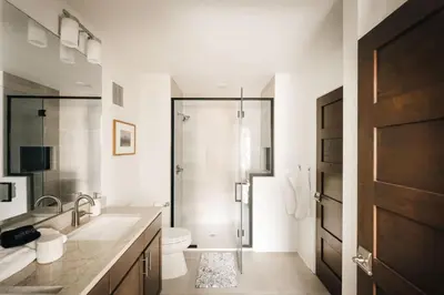 a white bathroom with a shower and a toilet at Refined Riverfront Living - King Suite & Views in Silverthorne
