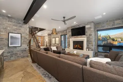 a living room with couches and a stone wall at LP Lakefront House - Private Dock, 7000+ Square Feet of Space, Stunning Views, Impeccable Quality in Grand Lake