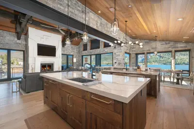 a large kitchen with wooden cabinets and a living room at LP Lakefront House - Private Dock, 7000+ Square Feet of Space, Stunning Views, Impeccable Quality in Grand Lake