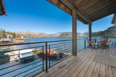 a deck with a view of the water and mountains at LP Lakefront House - Private Dock, 7000+ Square Feet of Space, Stunning Views, Impeccable Quality in Grand Lake