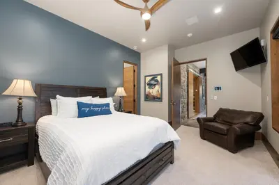 a bedroom with a large bed and a chair at LP Lakefront House - Private Dock, 7000+ Square Feet of Space, Stunning Views, Impeccable Quality in Grand Lake