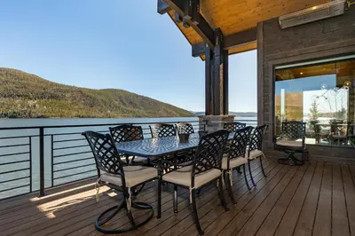 a table and chairs on a deck with a view of the water at LP Lakefront House - Private Dock, 7000+ Square Feet of Space, Stunning Views, Impeccable Quality in Grand Lake