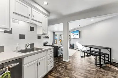a kitchen with white cabinets and a sink and a table at Treehouse C106 - Renovated Condo with Great Amenities, Central Summit County Location in Silverthorne