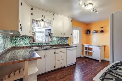 a kitchen with white cabinets and green tiles at Explore the Front Range! Lakewood Home with Yard in Lakewood