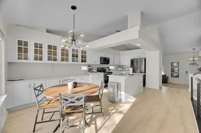 a white kitchen with a wooden table and chairs at Your Home Away From Home ! in DEN