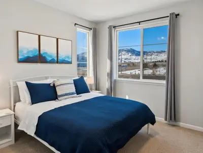 a bedroom with a bed with blue sheets and windows at Cozy Mountain View Getaway! in Arvada