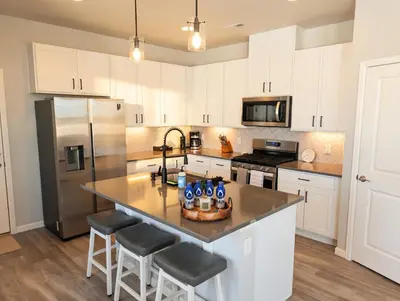 a kitchen with white cabinets and a stainless steel refrigerator at Cozy Mountain View Getaway! in Arvada