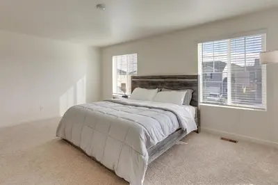a white bedroom with a large bed and two windows at Work and Play! Denver-Area Home with Fenced Backyard in Fort Lupton