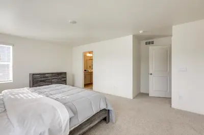 a white bedroom with a large bed and a doorway at Work and Play! Denver-Area Home with Fenced Backyard in Fort Lupton