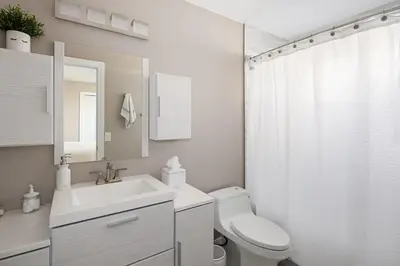 a white bathroom with a toilet and a sink at Mountain View Modern Oasis - Swim Spa -Steam -More in Broomfield