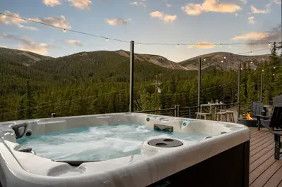 a jacuzzi tub on a deck with mountains in the background at Skyline Lodge with Private Sauna & Hot Tub in Idaho Springs