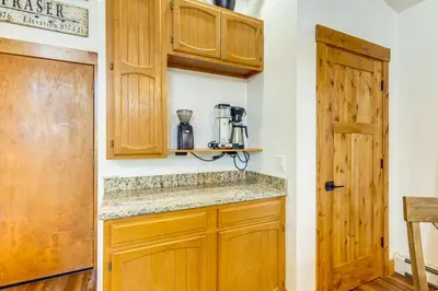 a kitchen with wooden cabinets and a door at Inviting and Cozy Fraser Condo Steps to Ski Shuttle in Fraser