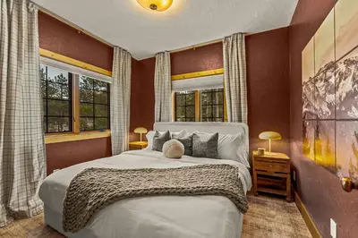 a bedroom with a large bed and two windows at Royal Elk Lodge Hot Tub Sauna Theatre Speakeasy in Bailey