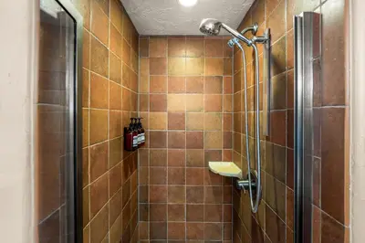 a bathroom with a shower with brown tiles at Royal Elk Lodge Hot Tub Sauna Theatre Speakeasy in Bailey