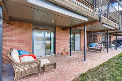 a patio with wicker furniture on a brick building at FoxGardens Incredible Lake & Mtn View Private Secure in Lakewood