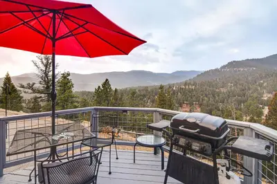 a grill on a deck with a red umbrella at Stunning Snowcapped Mtn Views! Evergreen Home in Evergreen