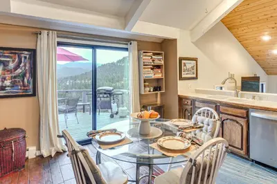a dining room with a table and a kitchen with a view at Stunning Snowcapped Mtn Views! Evergreen Home in Evergreen
