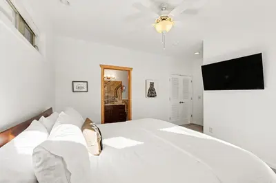 a bedroom with a white bed with a flat screen tv at Luxury Mountain Retreat Hot Tub Sauna Views in Estes Park