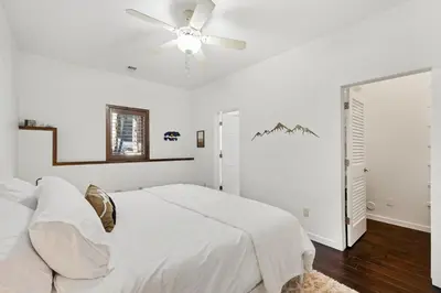 a white bedroom with a bed and a ceiling fan at Luxury Mountain Retreat Hot Tub Sauna Views in Estes Park