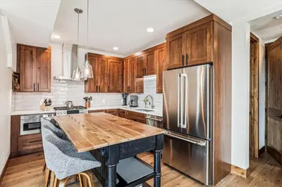a kitchen with a wooden table and stainless steel refrigerator at Experience the charm of Frisco in this spacious townhome, Decked Out Downtown, private hot tub in Frisco